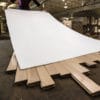 A man holds a white protective surface on a wooden floor.