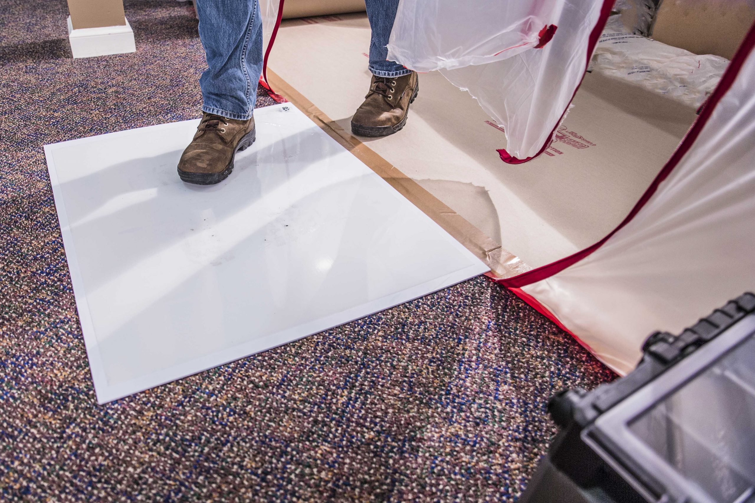 A man standing on a protective white surface over a carpet.