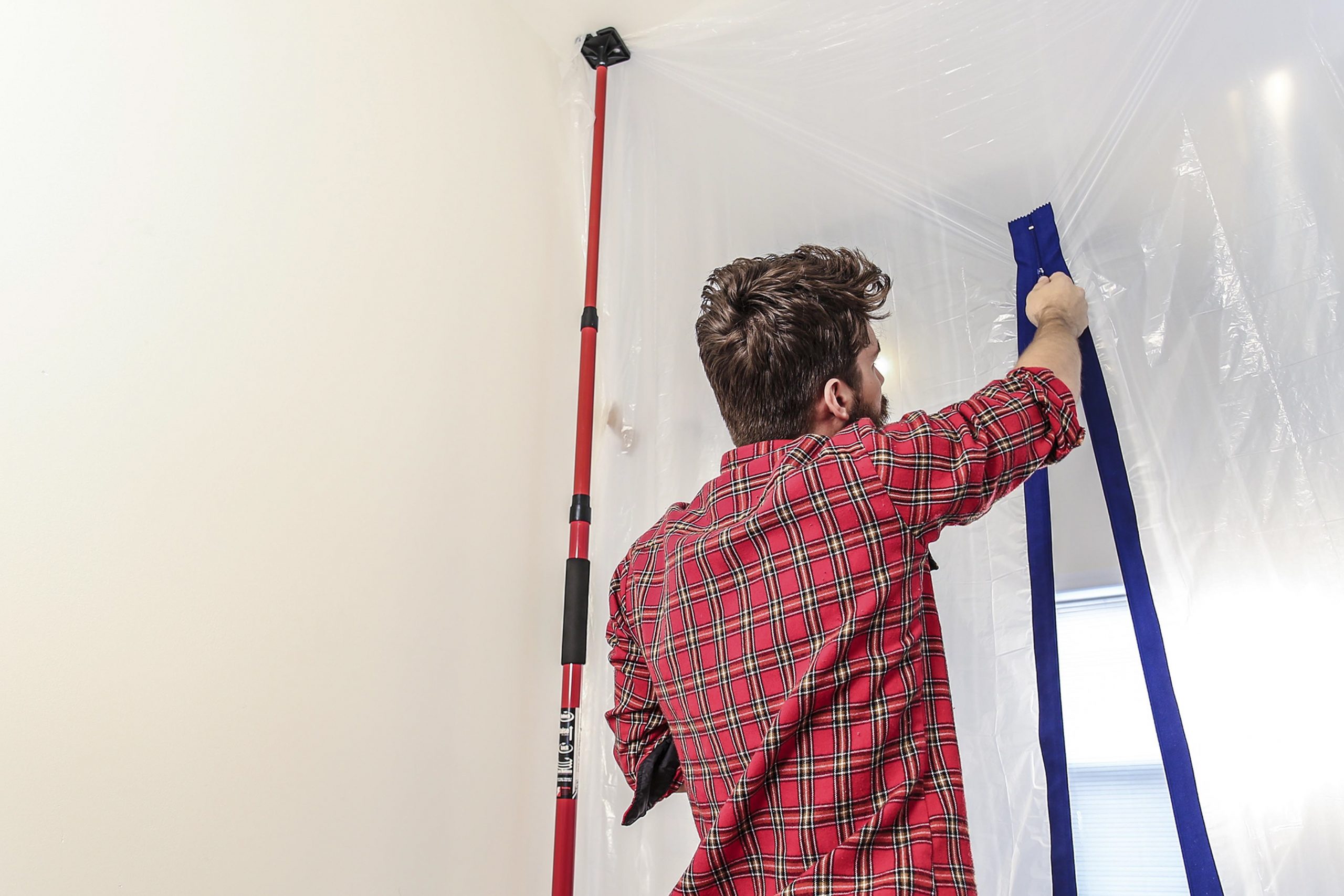 A man closing a plastic dust container curtain.