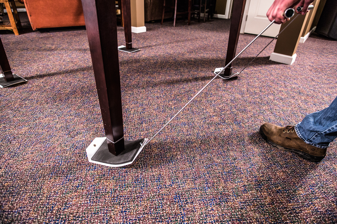 Two black plastic sleds, designed for moving heavy objects across a carpet surface.