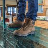 a close up of a person with work boots standing on a green, self adhesive surface protection film on a granite countertop.