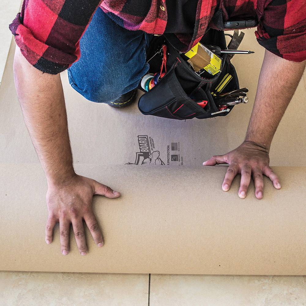 Person rolling Builder Board floor protection onto tile floor