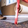 A man using a large self-adhesive protective film on a carpet.