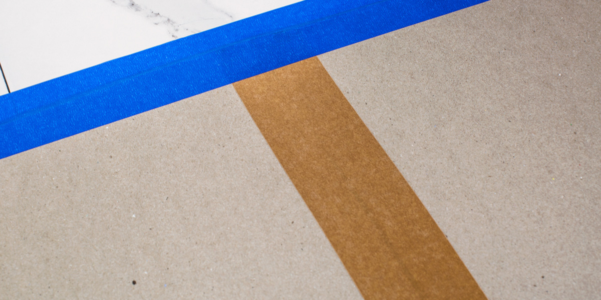 an intersection between a blue adhesive tape and a cardboard masking tape.