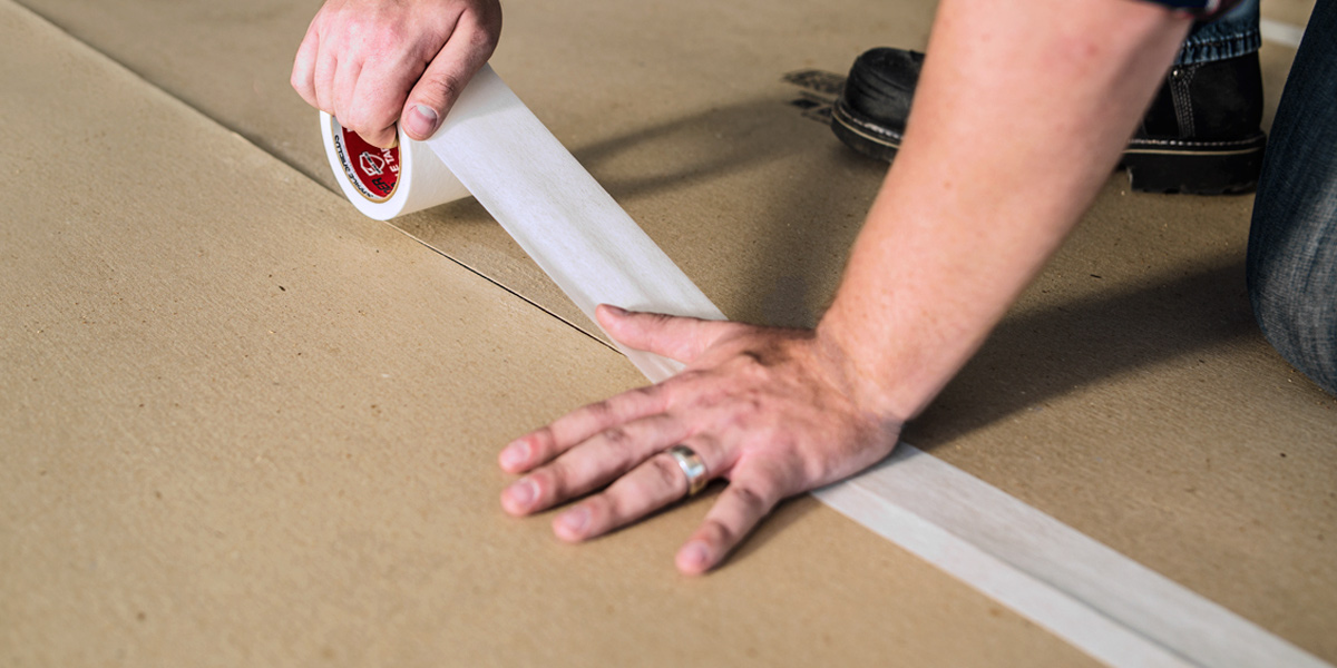 Man using duct tape to connect two protective surfaces.