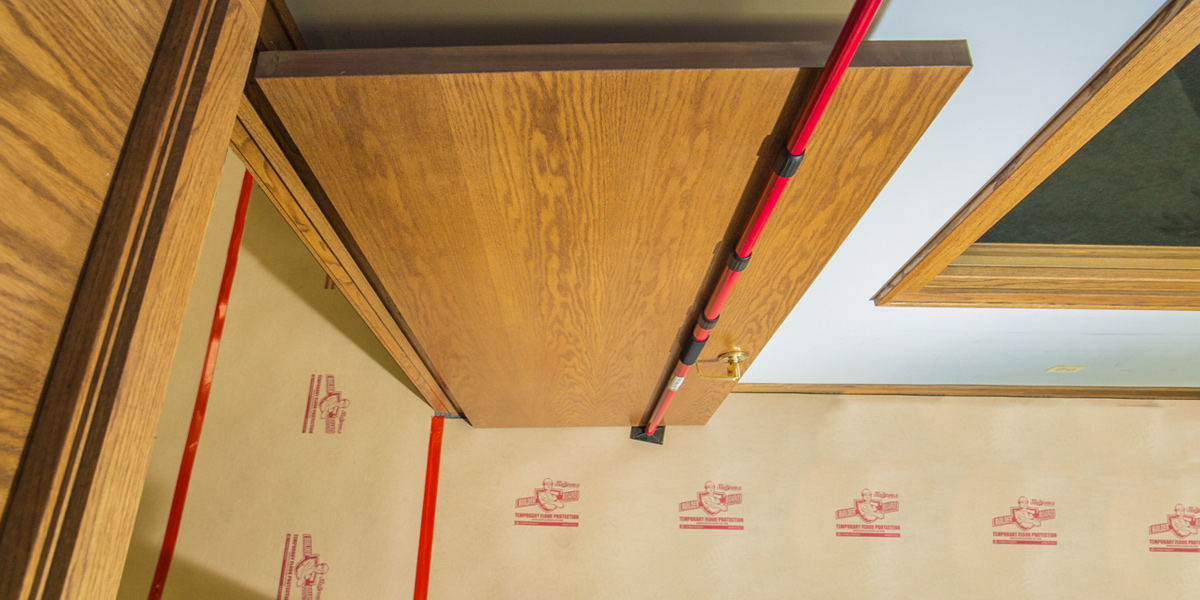 A photo from above of a door held by a red and black pole.