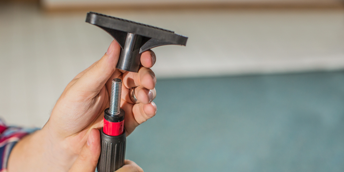 Photo of a man's hand as he puts on the screw base of a pole.