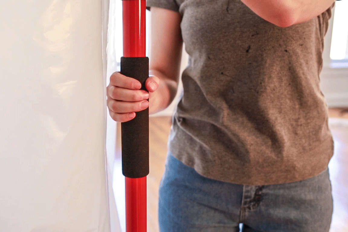 animated GIF of a person twisting a dust containment pole in order to increase tension with the ceiling