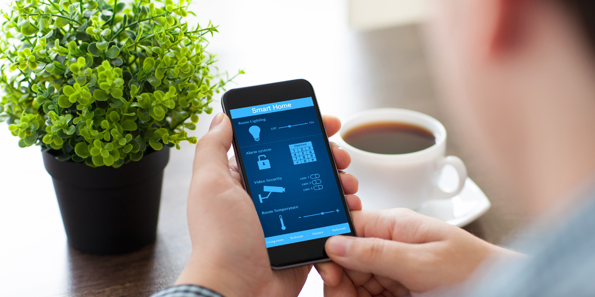 Photo from behind of a man looking at the cell phone application of a digital thermostat.