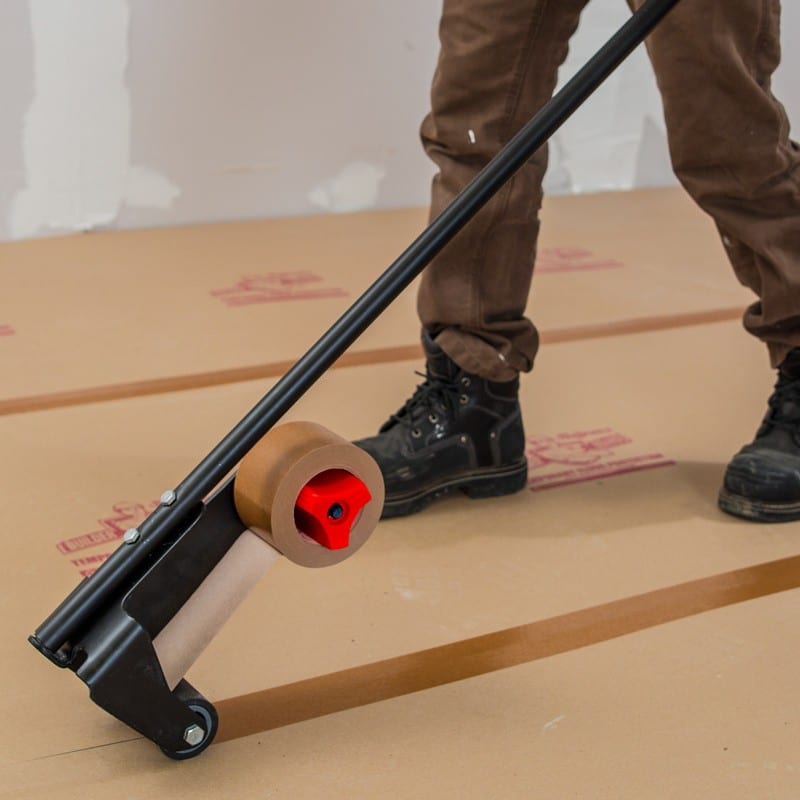 A man using a tape applicator to connect various protective surfaces.