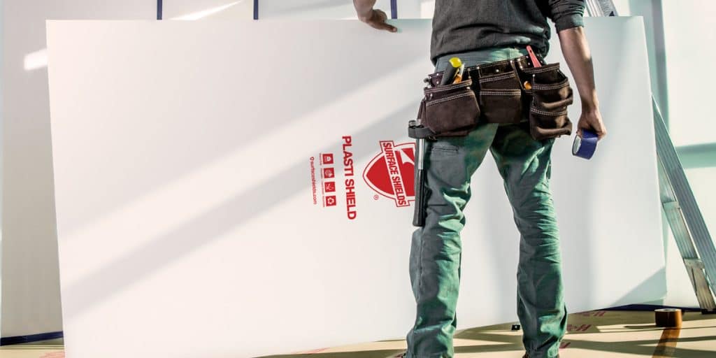 man with toolbelt holding corrugated plastic board