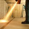 A man uses a metal polishing machine as filings fall onto a carpet protected by protective tape.