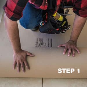 man rolling floor protection board, builder board, away from himself on the floor