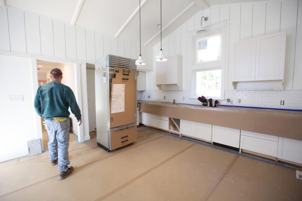 a contractor in a kitchen with floors, countertops, and appliances protection by temporary floor protection