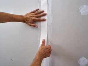 applying drywall tape to drywall sheet