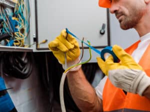 Electrician wrapping blue electrical tape around wires