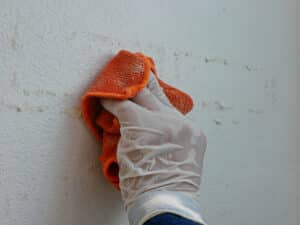 tape residue being removed from wall with a damp microfiber cloth