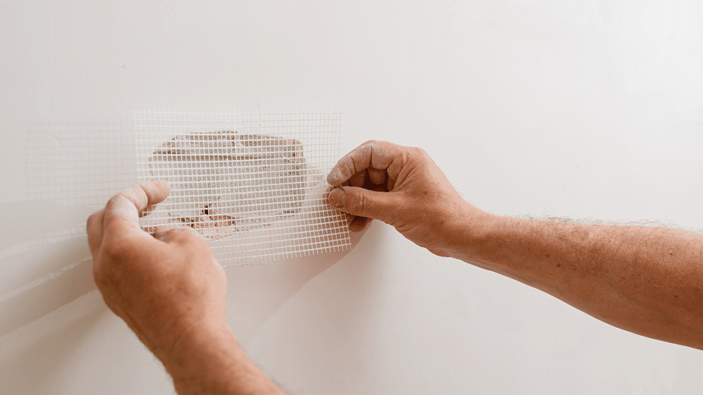 applying drywall mesh tape to repair hole in drywall