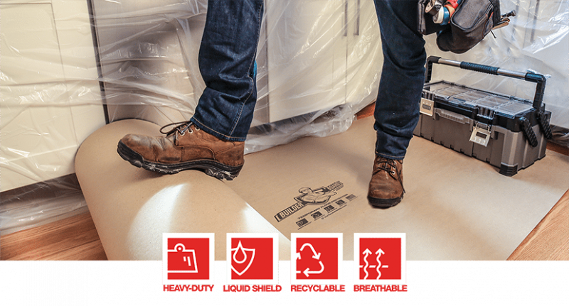 A man rolling out a roll of protective cardboard with his foot.